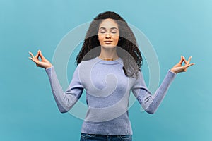 Serene young african-american woman in lavender sweater meditating with eyes closed