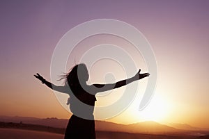 Serene young woman with arms outstretched doing yoga in the desert in China, Silhouette