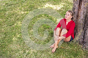 Serene young woman enjoying summer freshness under a tree