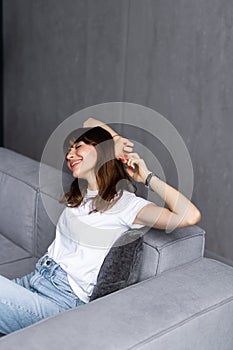 Serene young woman pretty relaxing on couch in living room. Calm woman freelancer crossing hands behind head, closing eyes and