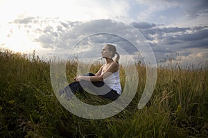 Serene young woman sitting in meadow