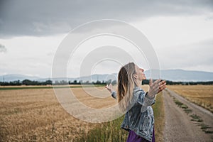 Serene young woman standing and meditating or practicing breathwork on a country road