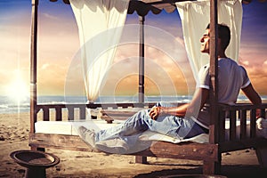 Serenity man relaxing on a canopy bed at the sunset beach