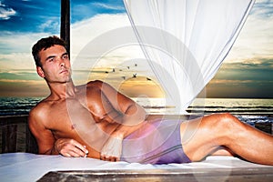 Serenity man relaxing on a canopy bed at the sunset beach