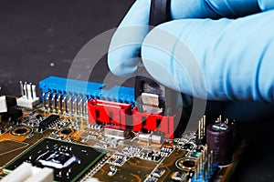 serial ata connection of cable with computer motherboard, hand of engineer with blue glove