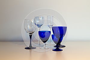 Series of blue stemmed glasses in different shapes and sizes set in soft light