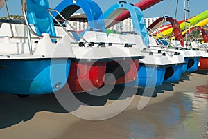 Series of colored pedal boats on the shoreline