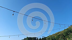 A series of decorative lights adorning the garden in the hilly area with a bright blue sky