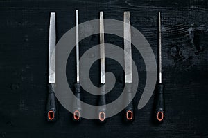 Series of many sharp steel blades on black wooden background
