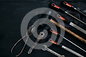 Series of many sharp steel blades and hammer on black wooden background