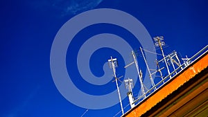 A series of non-centralized analog TV antennas in a building in an Italian city, with a blue sky