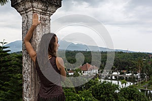 Series traveling girl in Asia. beautiful girl with long dark hair in elegant grey dress posing on old bridge in Tirta