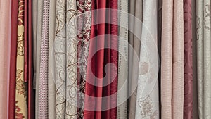 A series of vertically hanging various vivid curtains and portieres in gray, beige, brown and burgundy shades.