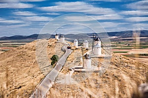 Series of windmill of Consuegra on the hill, in the foreground stalks of dry grass out of focus and in the background the plain of