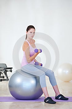 Serious about achieving her fitness objective. Portrait of a young woman sitting on an exercise ball and doing some