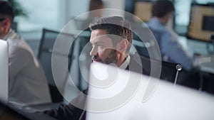 Serious Adult Bearded Man Working on Decktop Computer While Working in Big Open Space Office. Portrait of Positive