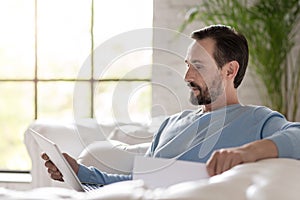 Serious adult man looking at his laptop