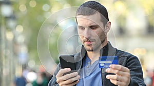 Serious adult man paying with credit card and phone