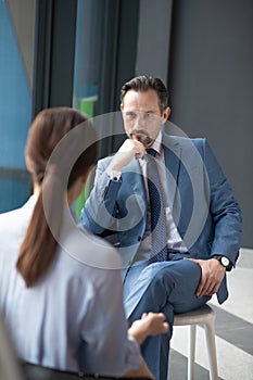 Serious affluent businessman listening to journalist asking him questions photo