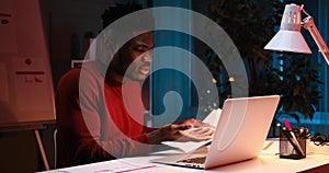 Serious African American businessman using laptop for video conference late night