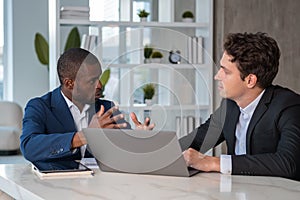 Serious African American businessman wearing formal suit talking to colleague