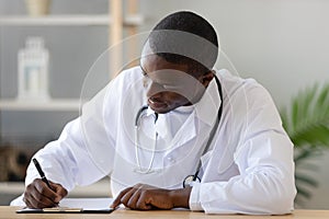 Serious African American doctor filling patient form document close up