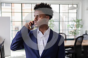Serious African-American employee talking on phone in office