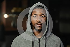 Serious African American male fitness instructor in grey activewear with hood