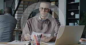 Serious African American man office worker reading documents looking at papers at desk