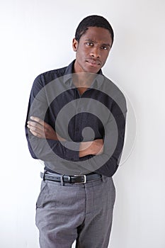 Serious african american man standing against white wall with arms crossed