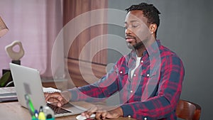 Serious african american man work on laptop typing sending message to client.