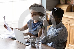 Serious African American married couple reviewing monthly bills