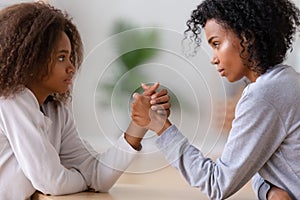 Serious african american mom and teen daughter arm wrestling