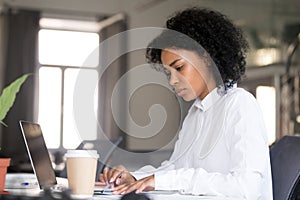 Serious African American woman working with documents at workpla