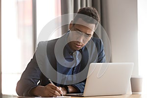 Serious african businessman ceo making notes working doing paperwork