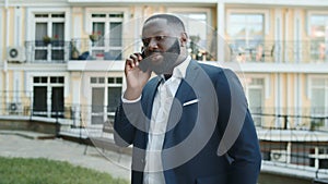 Serious african businessman talking on phone outside. Man having conversation