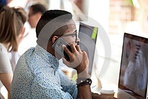 Serious african employee talking on phone consulting client in office