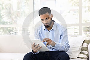 Serious African entrepreneur man using tablet for job communication