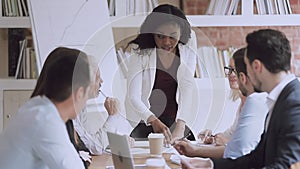 Serious african female business leader talking at diverse group meeting