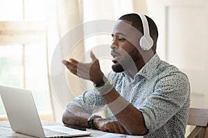 Samec učiteľ nosenie slúchadlá hovorenie pozerá na prenosný počítač 