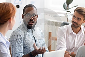 Serious african mentor explaining caucasian interns new strategy at meeting photo