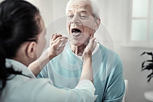 Serious aged man showing his tongue and doing nurses orders.