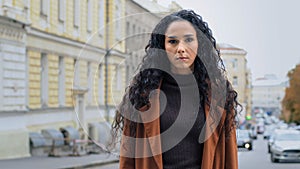 Serious alone confident powerful young brunette girl with long curly hair business woman with angry expression stands on