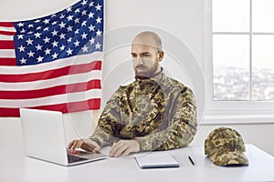 Serious American military student sitting at his desk and using his laptop computer