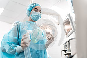 Serious anesthesiologist standing with the anesthetic mask in her hand photo