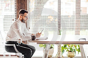 Serious applicant sitting in boardroom, preparing for interview with employer.