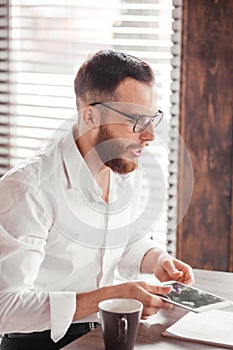 Serious applicant sitting in boardroom, preparing for interview with employer.