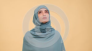 Serious Arab woman in doubt reflecting on beige background