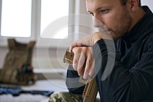 Serious army man with gun sitting at home