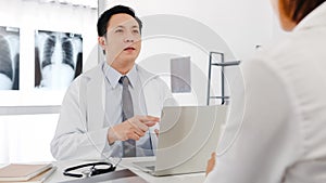 Serious Asia male doctor in white medical uniform using computer laptop is delivering great news talk discuss results or symptoms